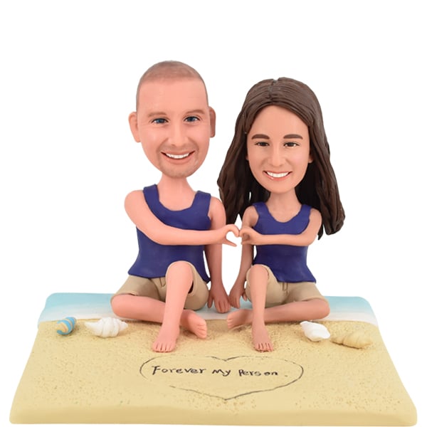 Couple Bobbleheads on beach showing heart